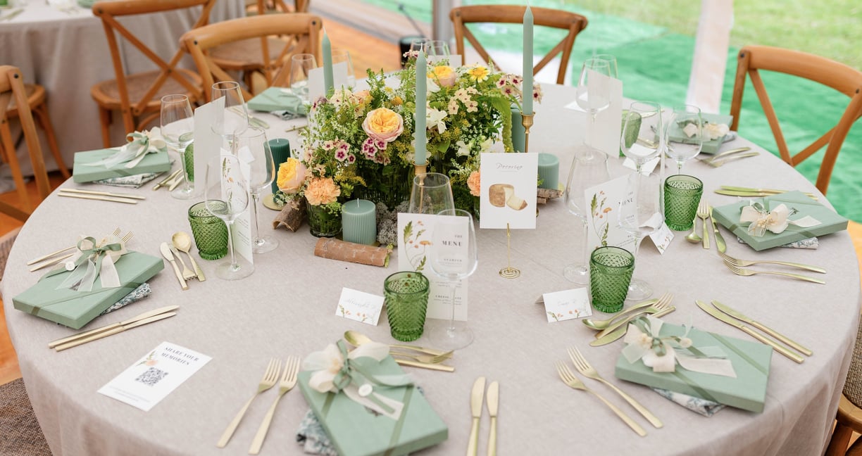 a table with a table setting with spring flowers and green glasses