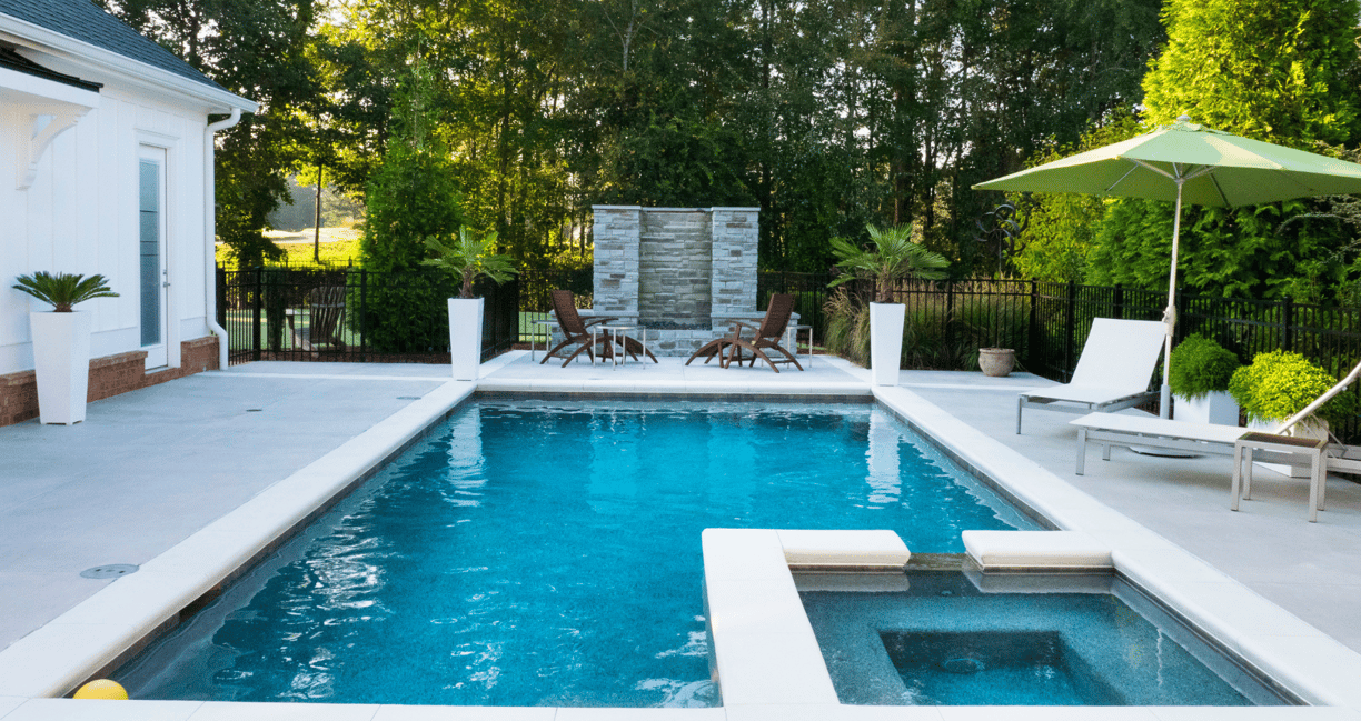 Horizontal image of a backyard setting featuring a ground-level pool and spa set-up.
