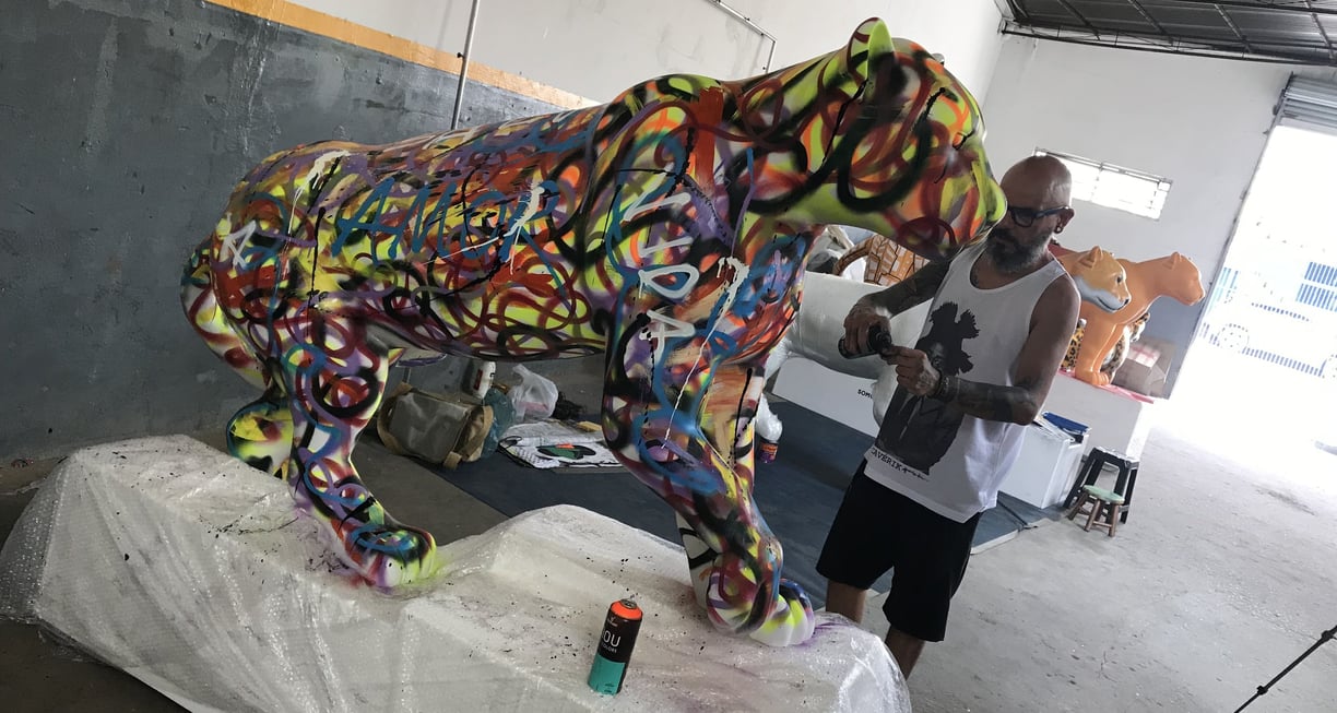 érgio Astral posando ao lado de sua criação, uma escultura de onça-pintada estilizada
