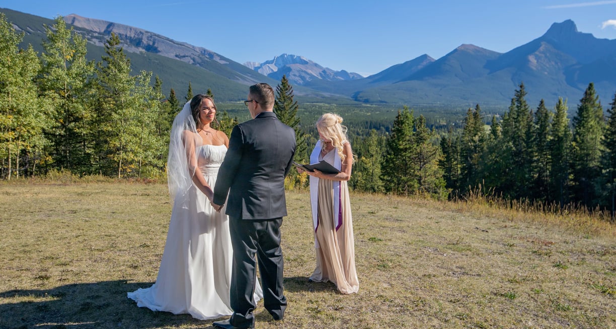 a bride and groom having a wedding ceremony in front of a mountain at Kananaskis village