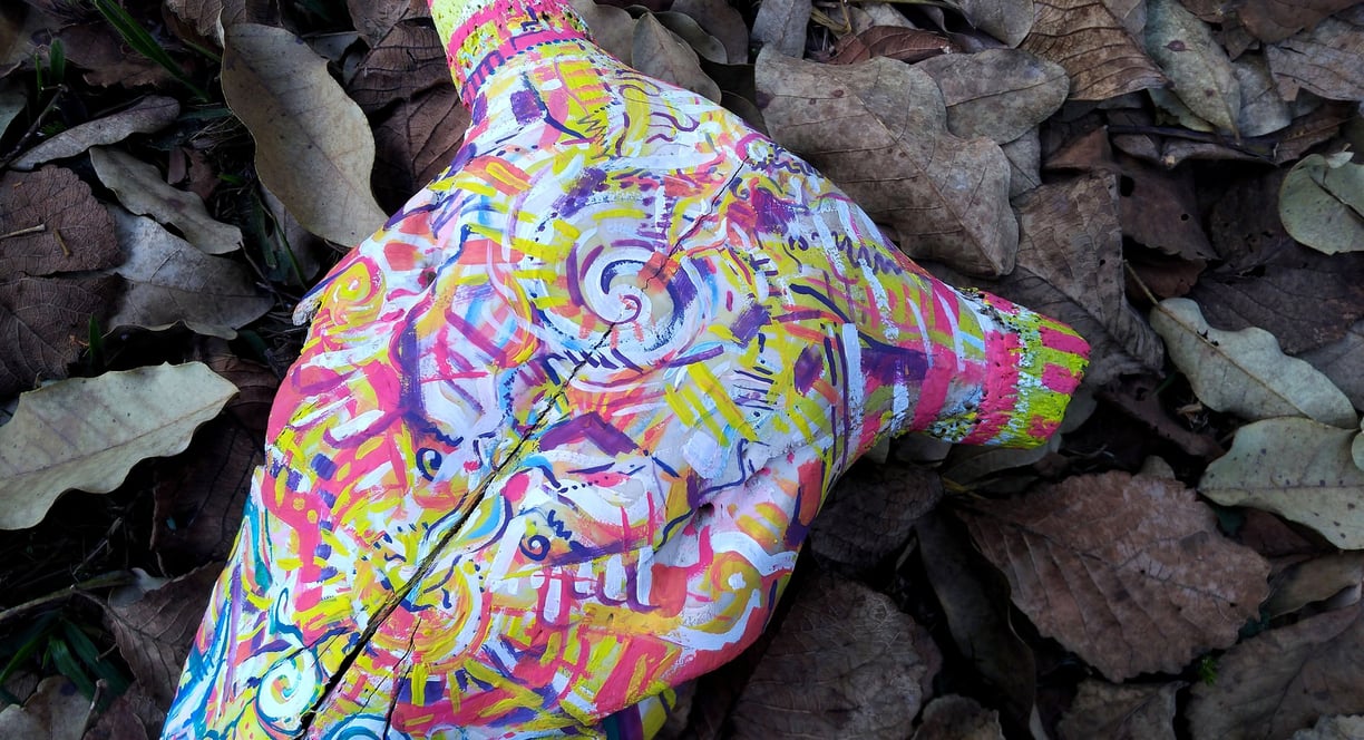 peinture aux couleurs vives sur un crane sur un lit de feuilles mortes