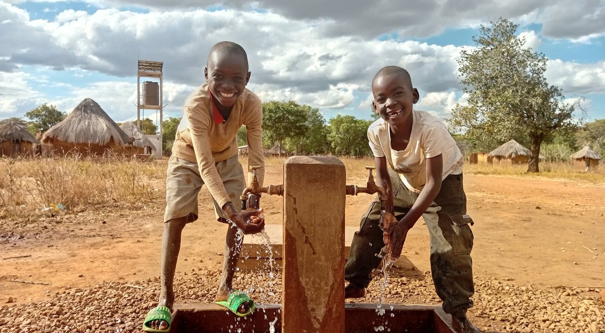 Children drinking clean water from a well in Africa