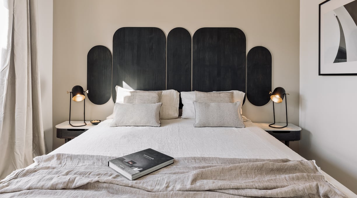 Vibrant bold black wood headboard design in a bedroom with neutral colours and natural materials