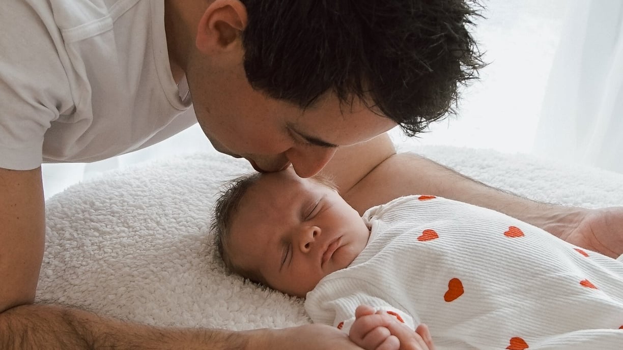 a man kissing a baby in a bed