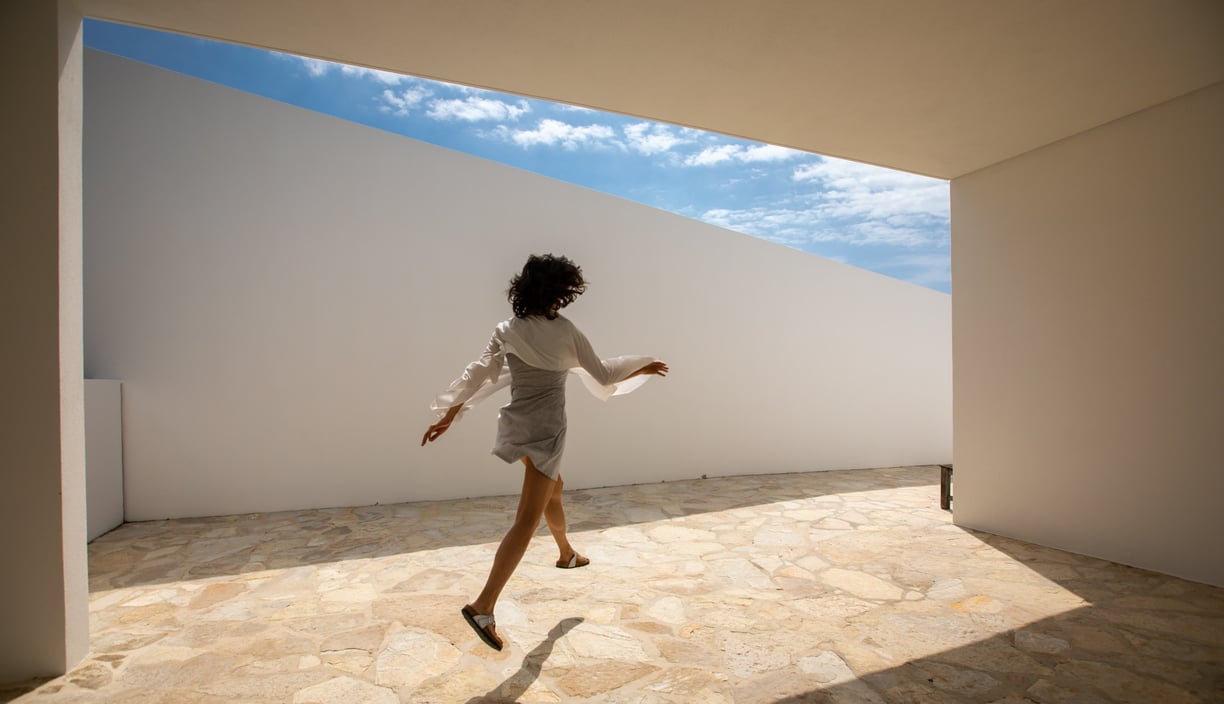 a woman in a white shirt and skirt jumping on a tiled floor in an architect house