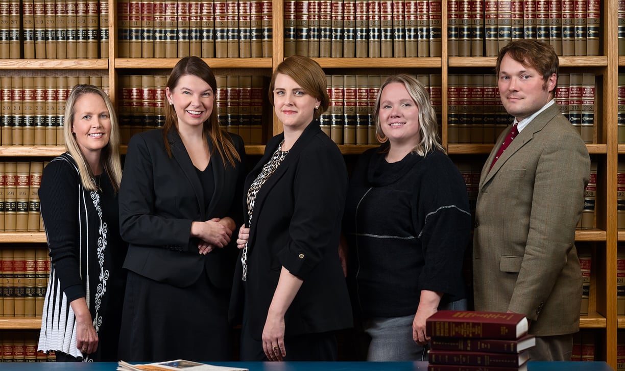 a group of people standing in front of a bookcase in a library
