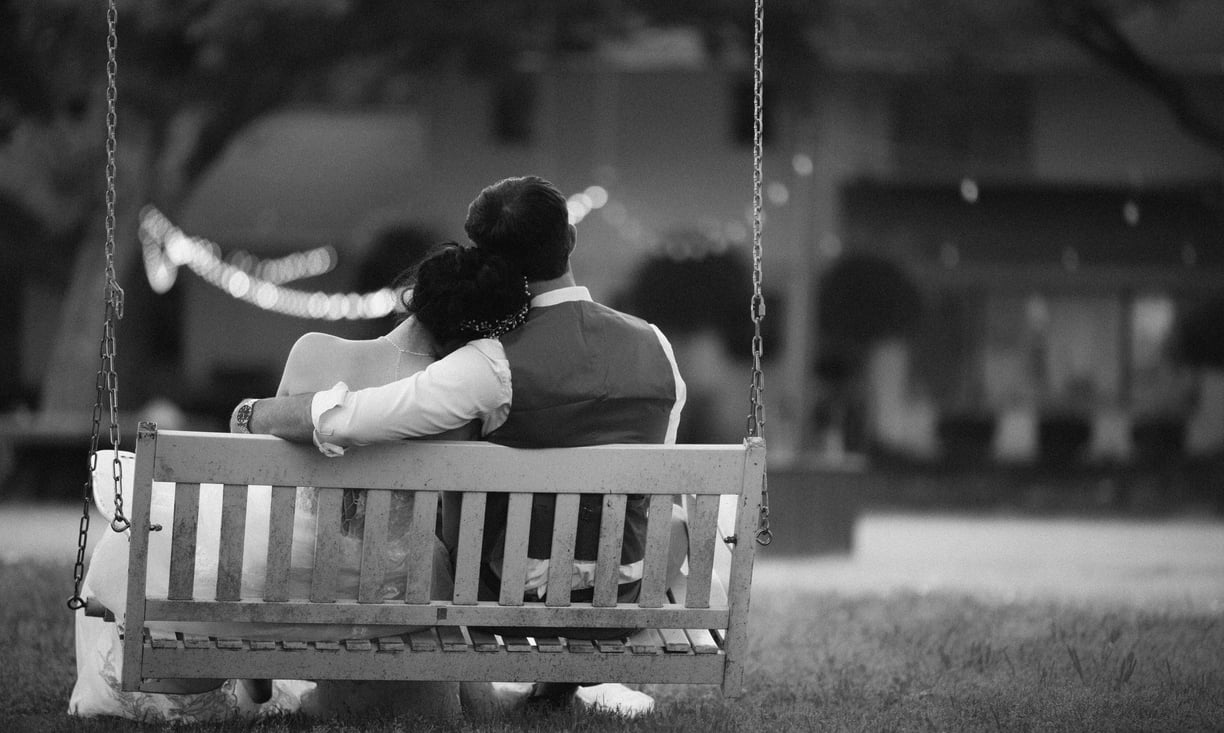 a couple sitting on a swing set in a park