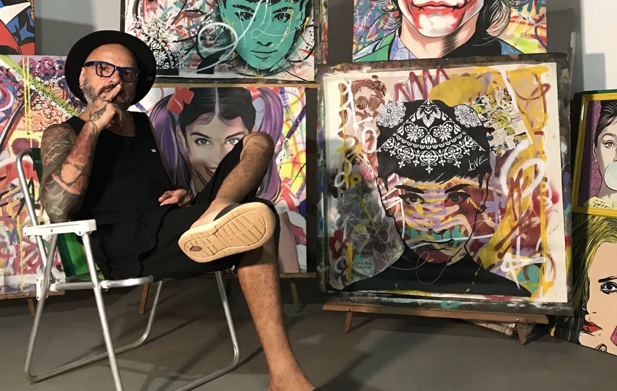 Sérgio Astral em seu estúdio, rodeado por suas obras de arte e materiais de pintura.