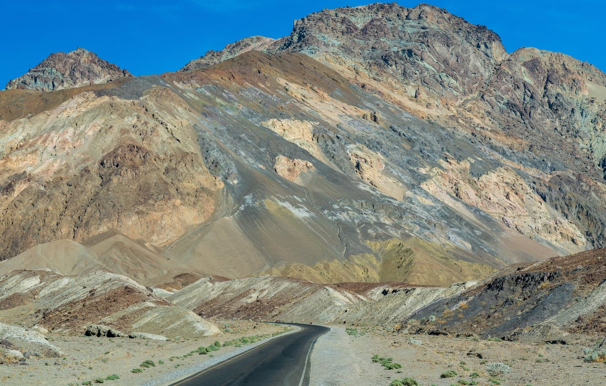 a road fading into the colorful facades of artists palette in death valley national park