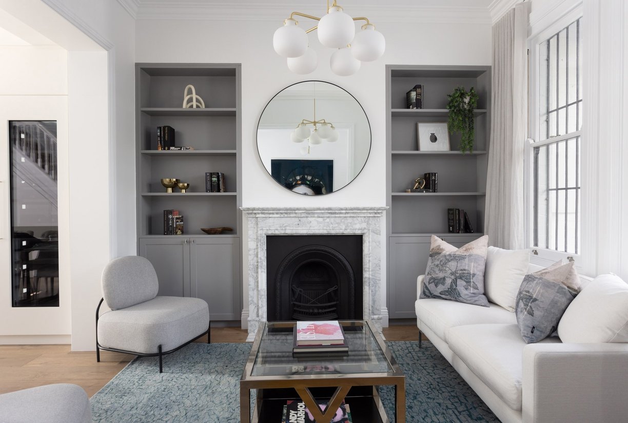 Freshly renovated Victorian lounge by Studio KENURO: fireplace, mirror, cozy furniture, bookshelves