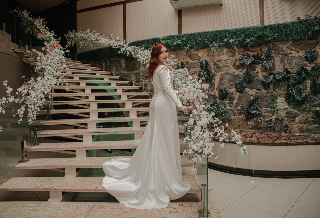 Noiva usa um elegante vestido de noiva do Ateliê Moncheri, com mangas transparentes e aplicações flo
