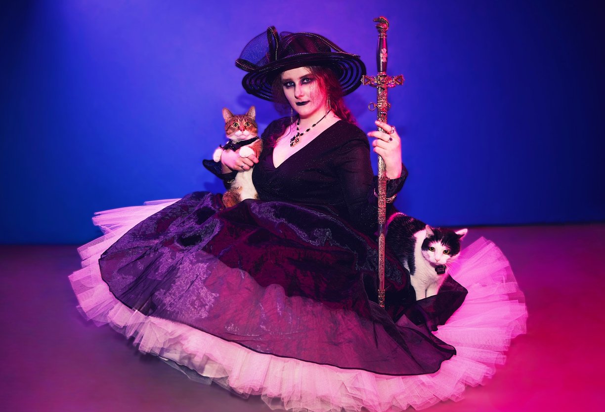 a woman in a witch costume holding a cat and a sword