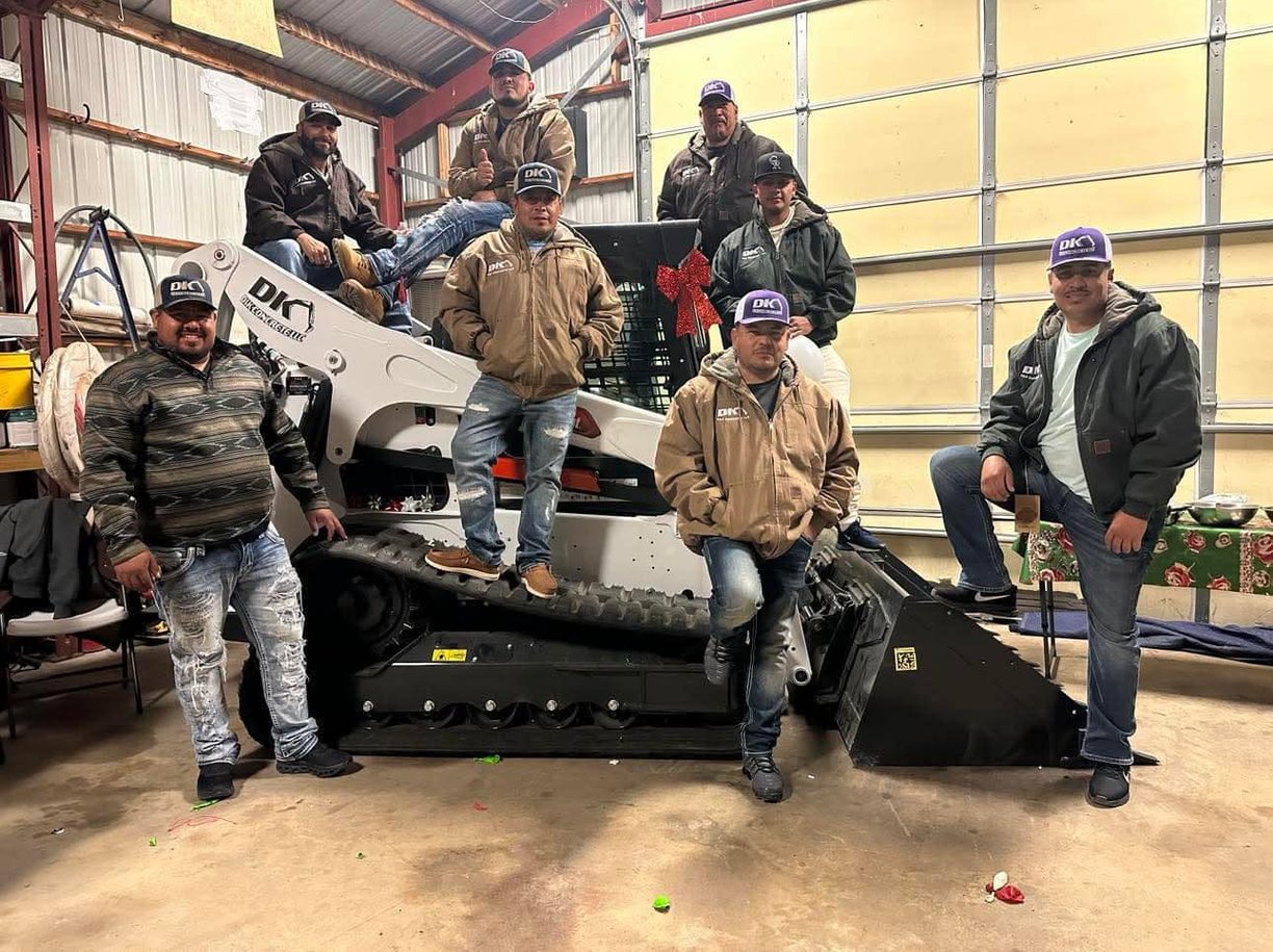 a group of men standing around a skid stear