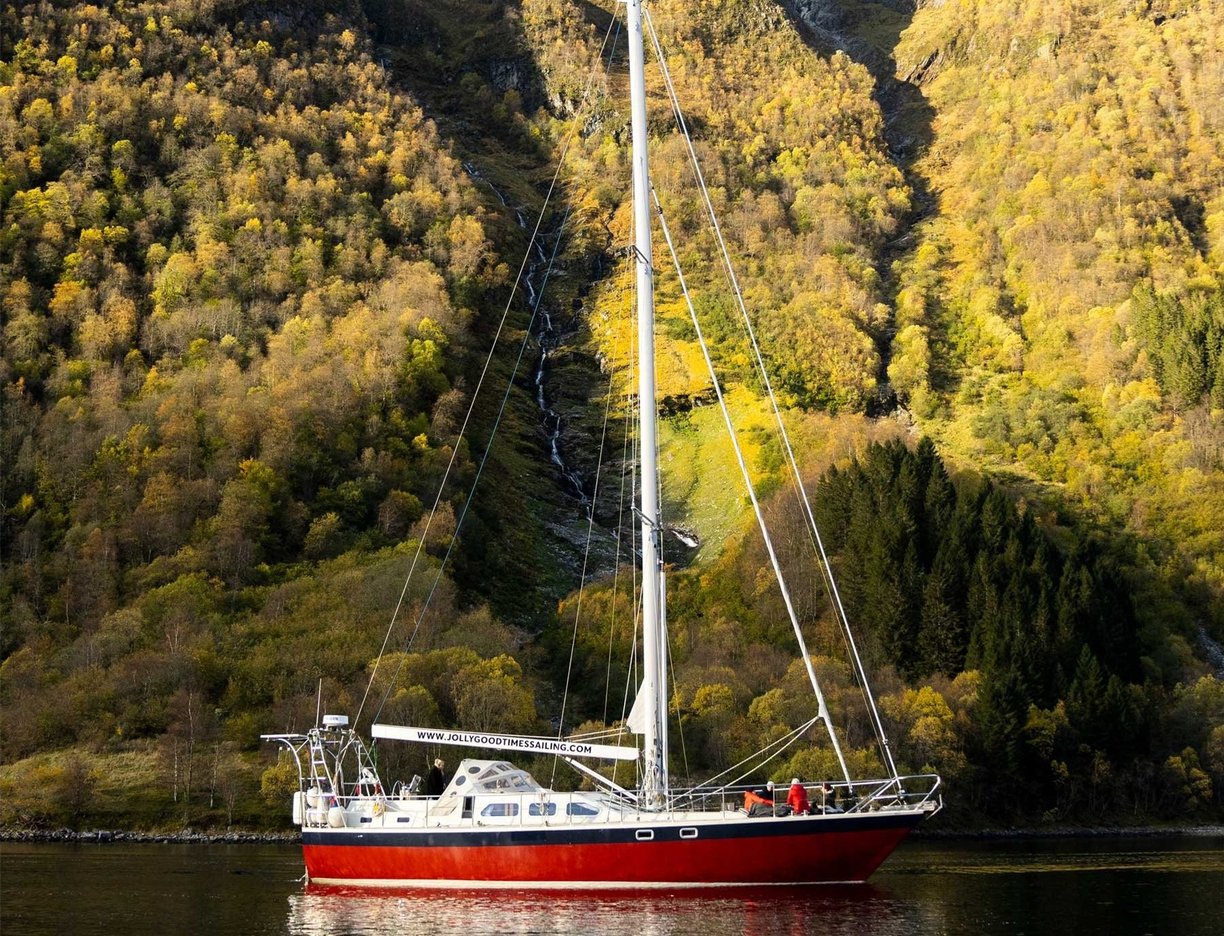 a sailboat in Norway in the water with a waterfall in the background | Sailing adventures in Norway 