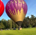 two hot air balloons in a field with a city skyline in the background