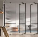 Puerta pivotante de cristal con marco negro en pasillo luminoso de diseño minimalista