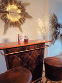 Eine braune Bar, auf der ein roter Smoothie steht, an der Wand hängt ein rundes Schild mit dem LOGO