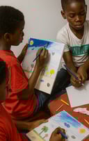 un groupe d'enfants des ateliers créatifs sont assis autour d'une table et dessinent