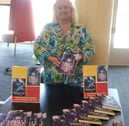 a woman standing in front of a table with booksks and a book