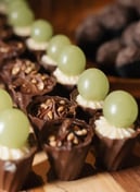 Imagem de deliciosos doces decorados com uvas verdes e cobertura de chocolate, perfeitos para festas