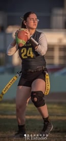 a woman in a black and white uniform holding a football ball