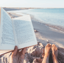 a person reading a book on a beach