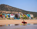 a person holding a surfboard while walking on the beach