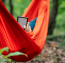 a person reading on an ereader in a hammock