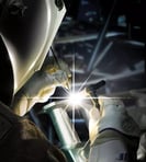 a person welding a piece of metal with a light shining on the side