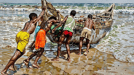 a group of men are pushing a boat in to the water