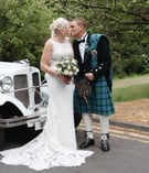 a bride and groom standing next to a car