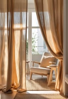 A sheer linen curtain softly sections off a cozy reading nook in a sunlit apartment.
