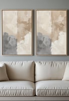 Pair of neutral-toned abstract canvas prints above a light beige sofa.