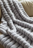 Striped grey throw blanket draped over a beige couch.