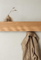 A compact wooden wall shelf with hooks underneath, blending storage and display.
