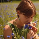 a woman in a yellow dress is holding a flower