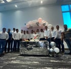 a group of men standing around a table with balloons