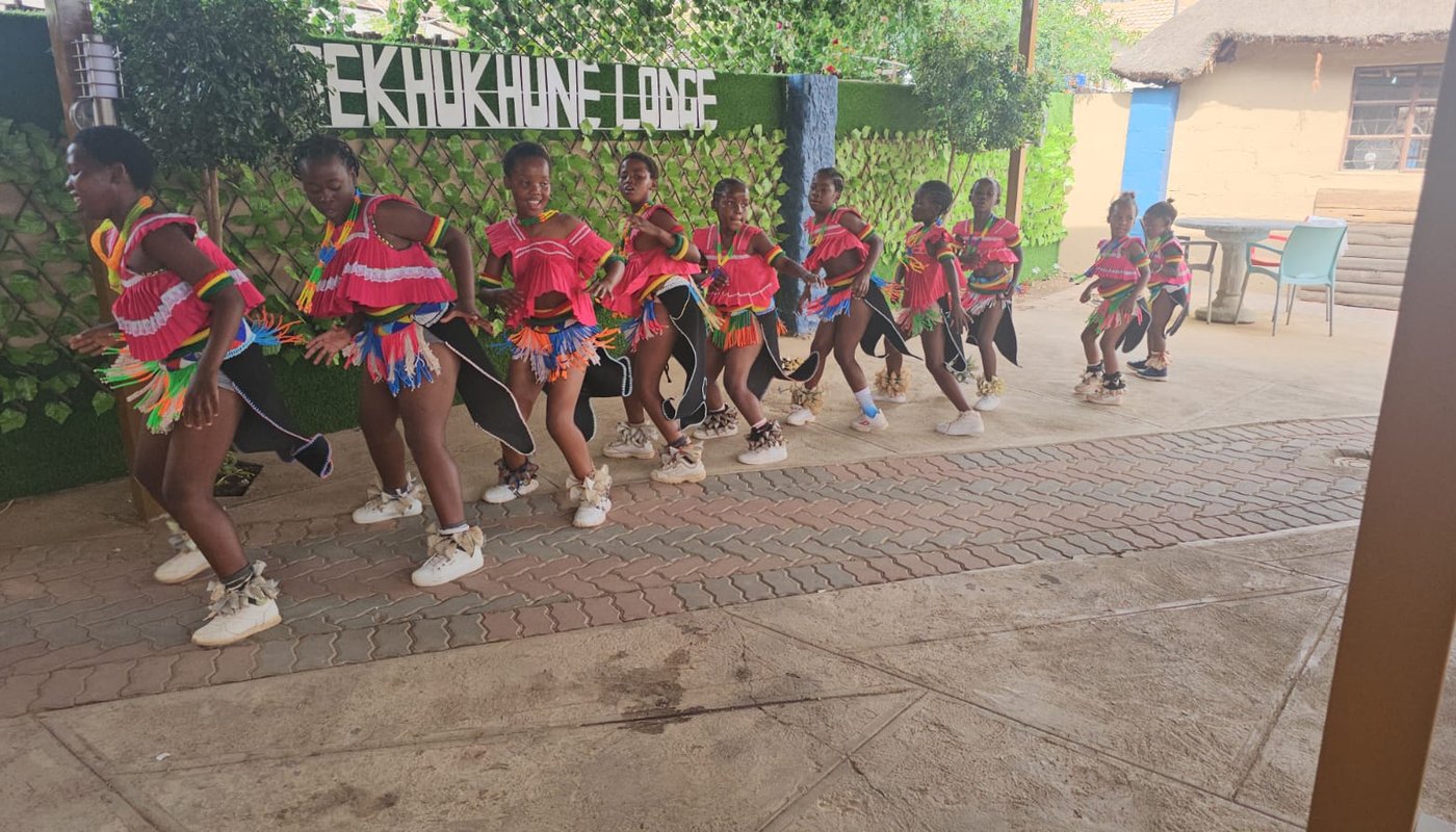Local dance troupe performing in traditional dress at the lodge entrance