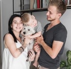 a man and woman holding a baby and a dog