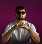 An attractive Young man wearing sunglasses with a purple background