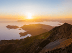 a mountain scene with a sunset over the ocean