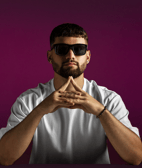 An attractive Young man wearing sunglasses with a purple background