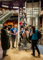 People passing a film festival volunteer and lining up in an escalator leading to a movie theatre