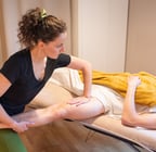 Masseuse en fente avant qui étire l'adducteur d'un client allongé sur le dos