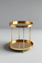 Round gold side table with two trays, shown on a light grey background.
