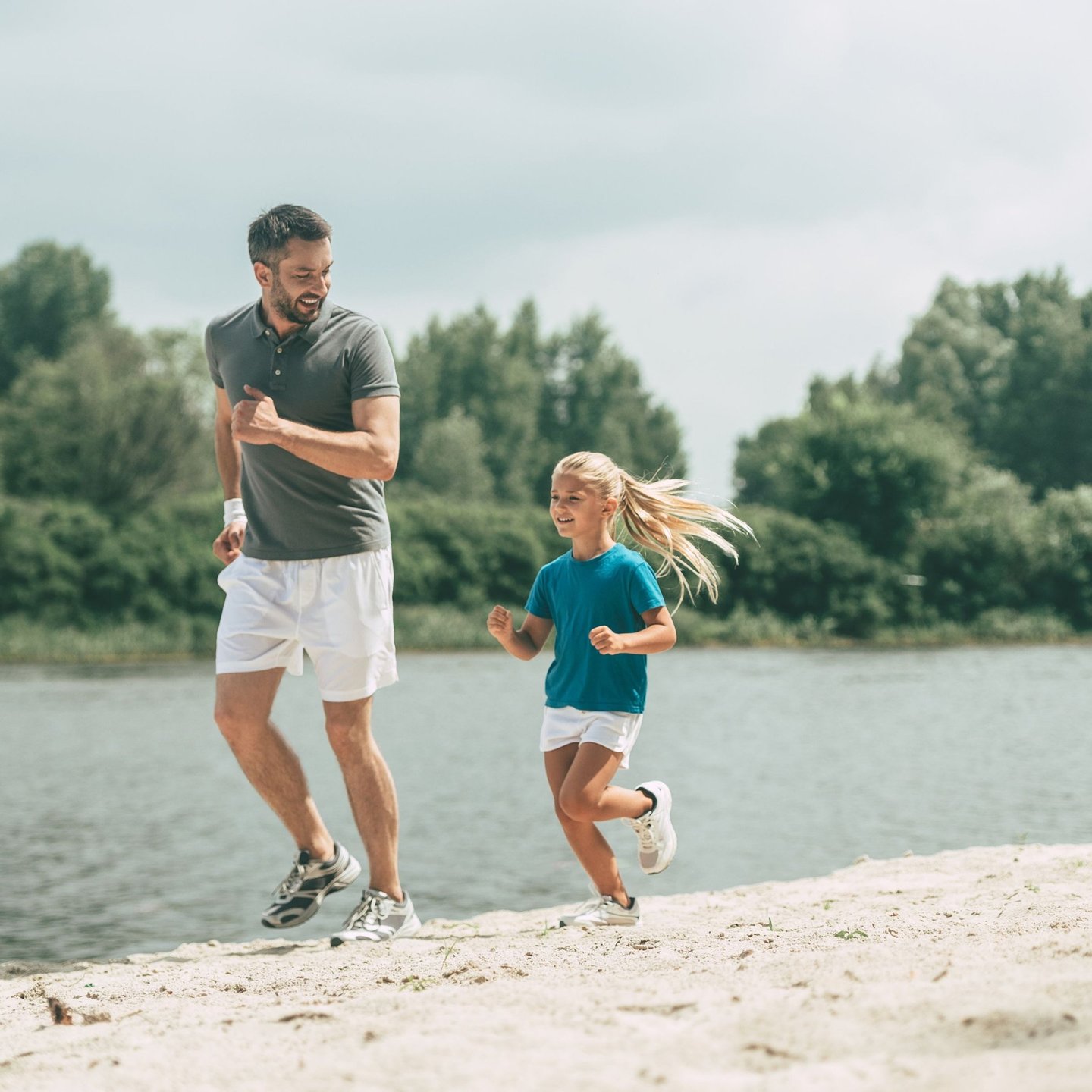 Father and daughter jogging together along a riverside path