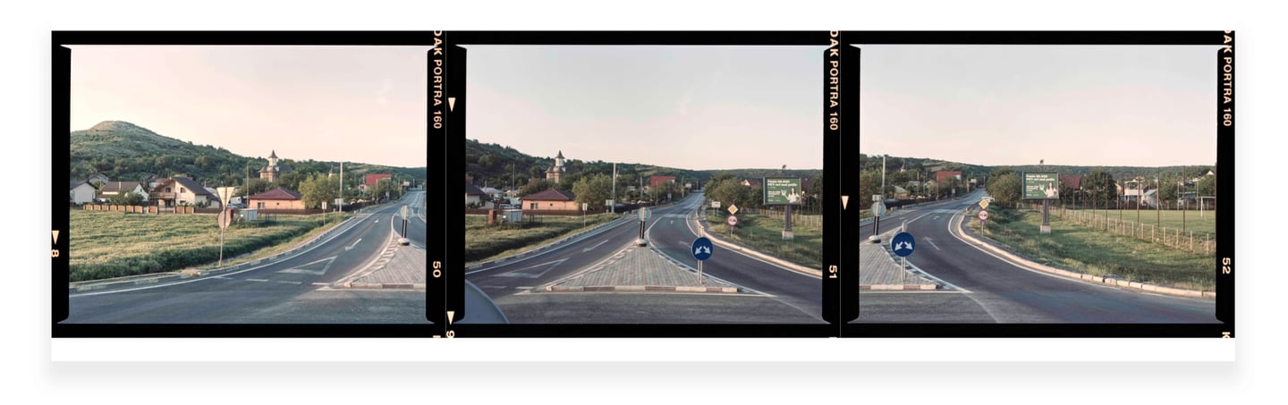 Composite photo of a countryside road intersection, golden hour, clear skies, lush greenery, road signs, distant houses