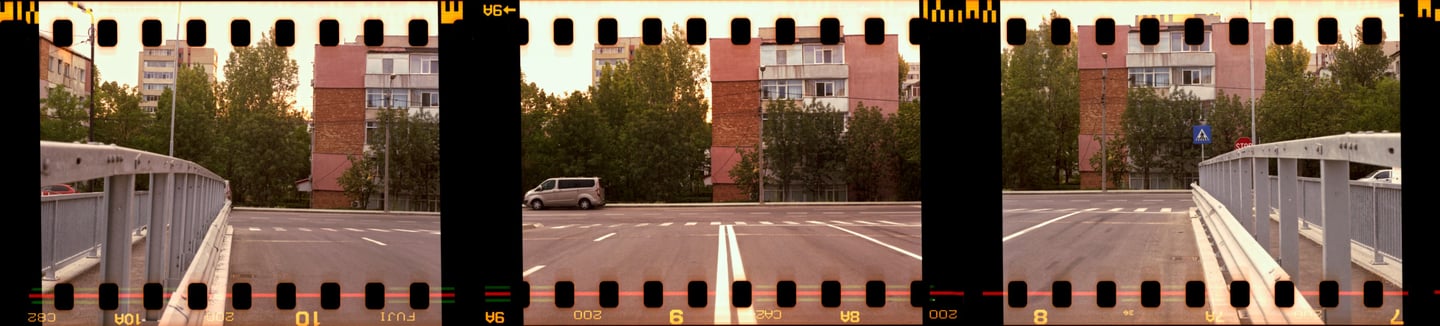 Composed photo of a street scene with a car and buildings captured in film strip