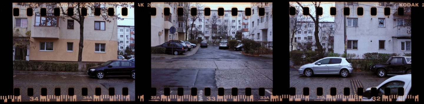 Composed photo of a urban street scene with parked cars and buildings, film strip 