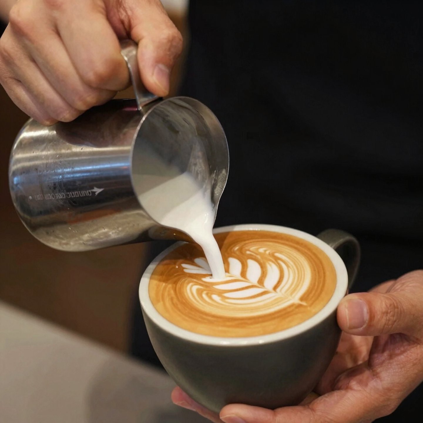 Arte latte en tazas sobre barra moderna verde. Café de especialidad en Playa del Carmen, México.